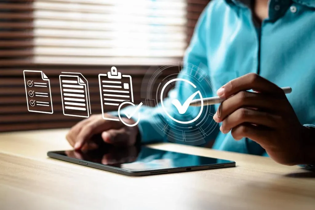 Person using a stylus on a tablet with digital checklist and approval checkmark icons overlaid